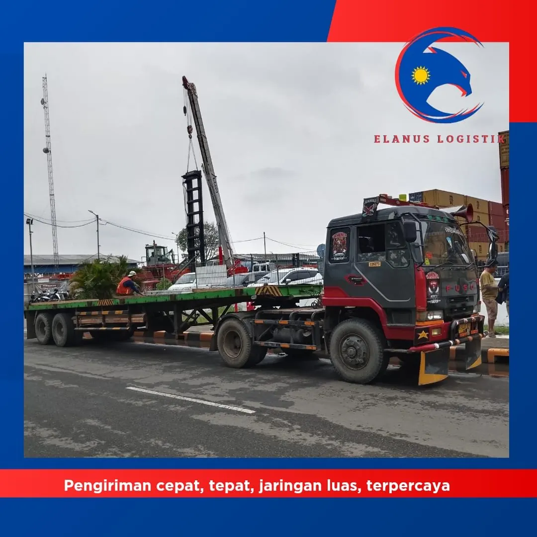 Truck Fuso merah dengan crane mengangkat barang berat, operasi pengiriman ELANUS LOGISTIK